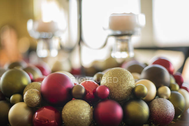 Close-up of colorful Christmas ornaments and candles in candle holder on table. — Stock Photo