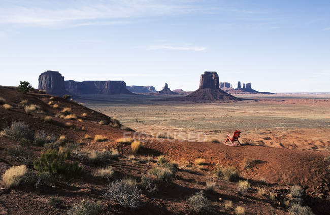 Landscape and eroded sandstone buttes in Monument Valley with single wooden chair. — Stock Photo