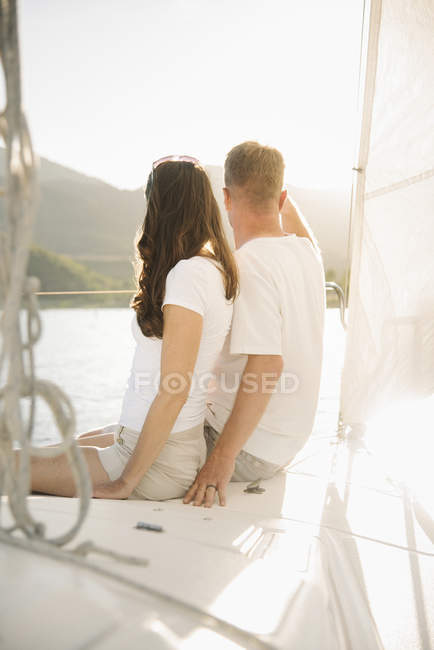 Mature couple sitting together on sailboat and looking at view on lake. — Stock Photo