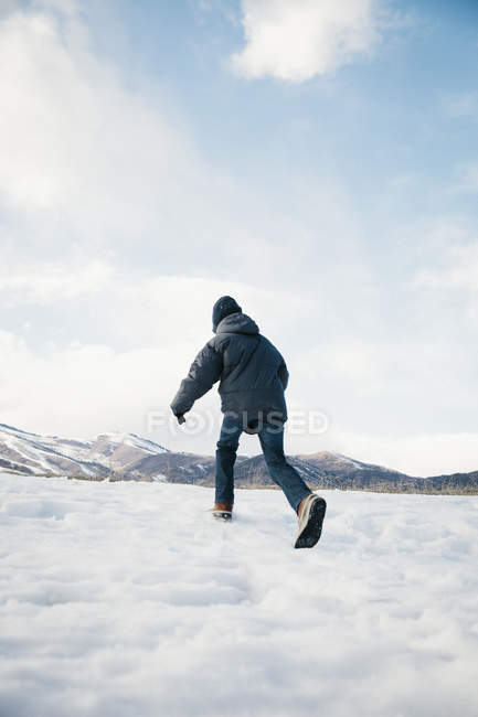 Boy running away across snow field. — Stock Photo