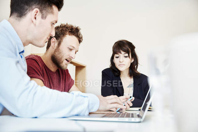 Chers collègues assis à table lors d'une réunion d'affaires et utilisant un ordinateur portable . — Photo de stock