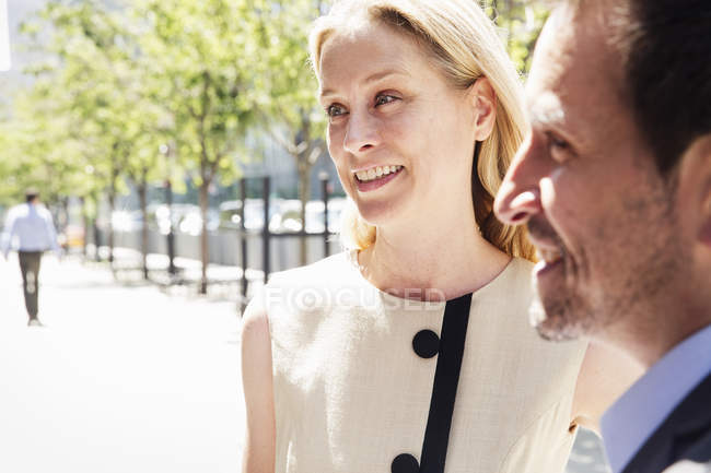 Smiling businesswoman and businessman standing on street. — Stock Photo