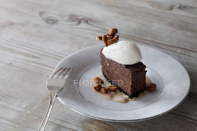 Slice of  chocolate mousse dessert with ice cream, nuts and sauce on plate. — Stock Photo