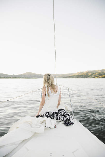 Loira adolescente sentada no veleiro arco no lago . — Fotografia de Stock