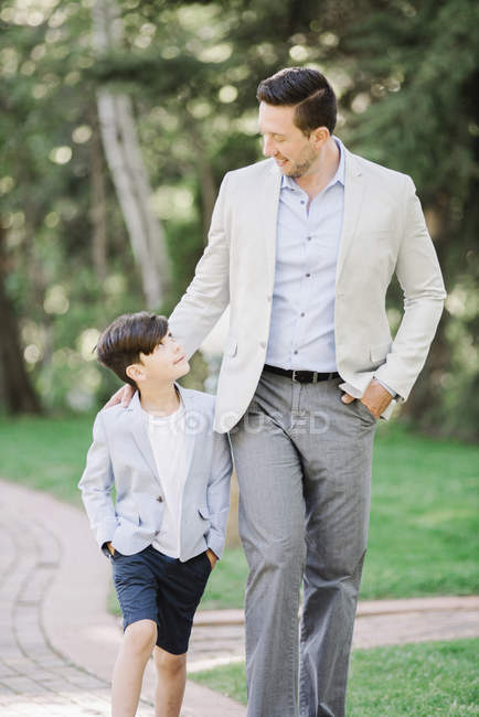Padre e hijo caminando por el camino en el jardín . - foto de stock