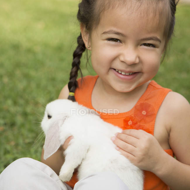 Vorschulmädchen hält weißes Kaninchen im Freien. — Stockfoto