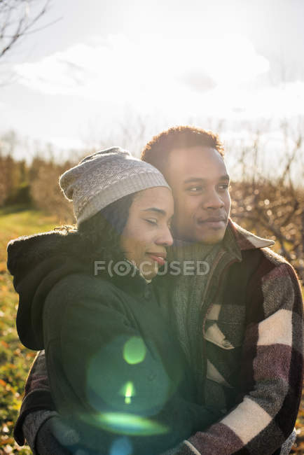 Junges Paar umarmt sich in sanftem Licht im Obstgarten im Winter. — Stockfoto