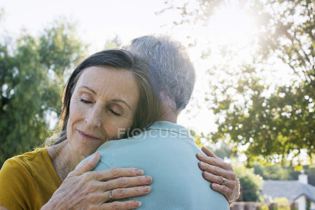 Senior couple hugging outdoors, low angle view. — Stock Photo