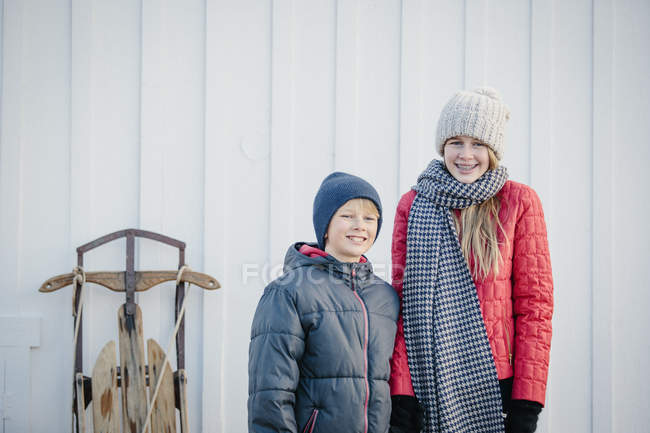 Brother and sister side by side in country yard in winter. — Stock Photo
