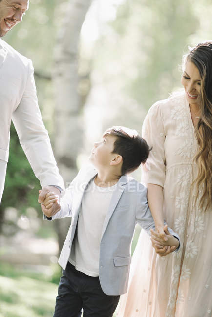 Père, mère et fils marchant et se tenant la main dans le parc . — Photo de stock