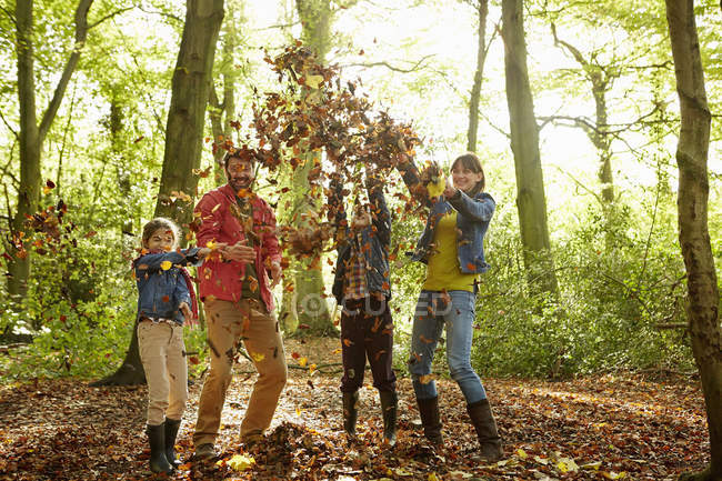 Осенью семья выбрасывает сухие листья в воздух в лесу . — стоковое фото