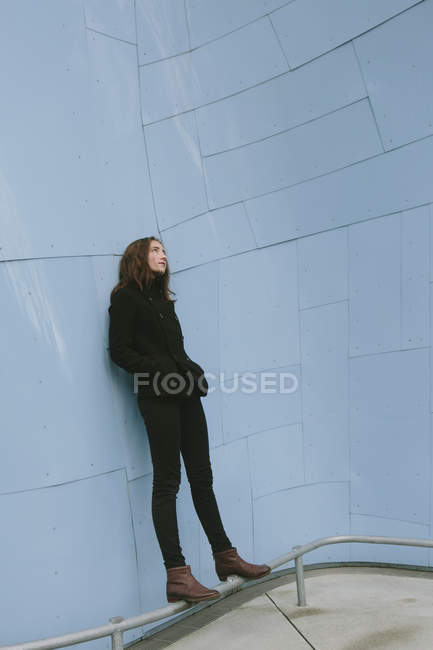 Teenage girl standing against modern building wall. — Stock Photo
