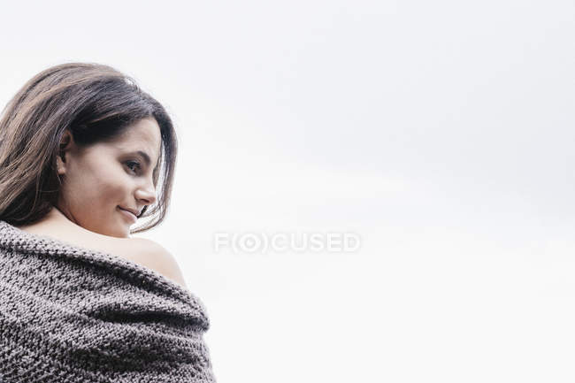 Woman with long brown hair wrapped in blanket looking over shoulder. — Stock Photo