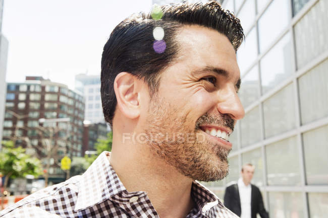 Porträt eines lächelnden Mannes mit braunen Haaren und Stoppeln im karierten Hemd. — Stockfoto