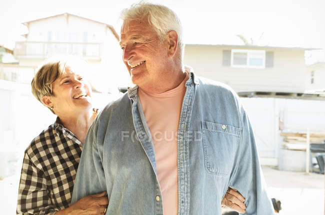 Seniorenpaar lächelt und schaut sich in Wohnhaus an. — Stockfoto