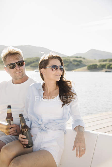Uomo e donna seduti sulla barca a vela e a bere birra . — Foto stock