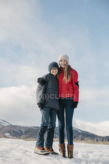 Irmão e irmã de pé lado a lado na paisagem nevada
. — Fotografia de Stock
