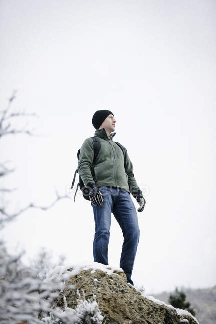 Homem de casaco de lã e chapéu carregando mochila, visão de baixo ângulo . — Fotografia de Stock