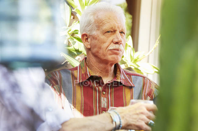Uomo anziano con i baffi seduto all'aperto . — Foto stock