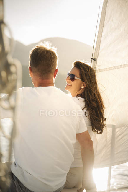 Man and woman relaxing under sail on boat on lake. — Stock Photo