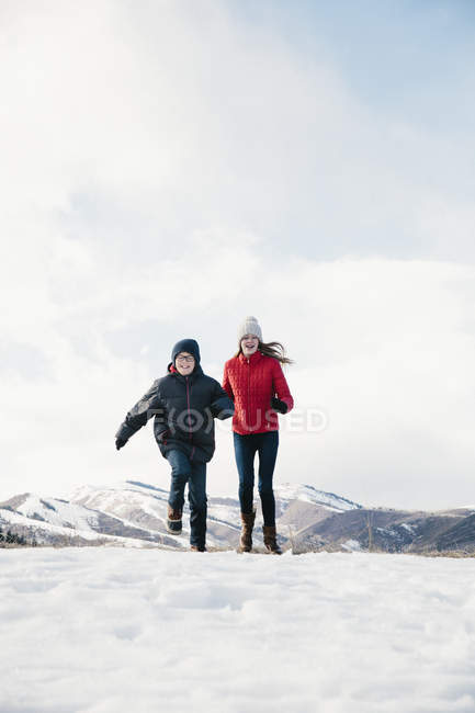 Fratello e sorella che corrono attraverso il campo di neve
. — Foto stock