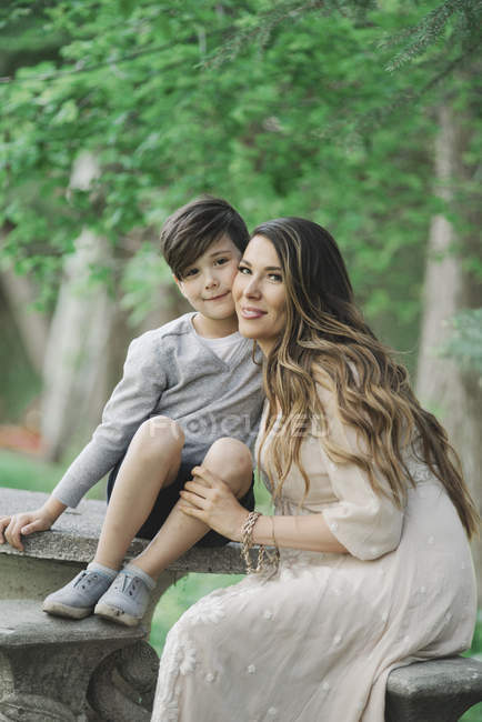 Smiling mother and elementary age son sitting in garden. — Stock Photo