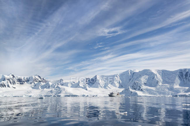 Polar research vessel in Antarctic landscape with snow-capped rocks and icebergs. — Stock Photo