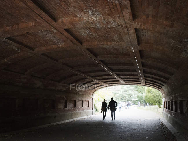 Couple holding hands while walking through tunnel in Central Park, Manhattan, New York, USA. — Stock Photo