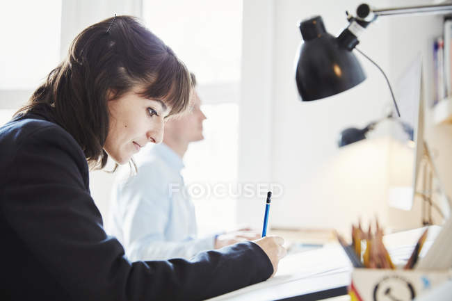 Donna che lavora alla grafica sul tavolo da disegno in ufficio . — Foto stock