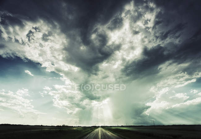 Дорога тянется к горизонту под драматическим небом
. — стоковое фото
