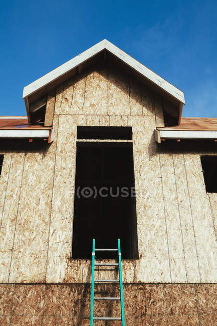 Maison en construction avec échelle menant à une grande fenêtre, vue à angle bas . — Photo de stock