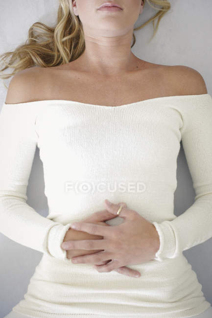 Blonde mid adult woman relaxing on back with hands folded on stomach. — Stock Photo