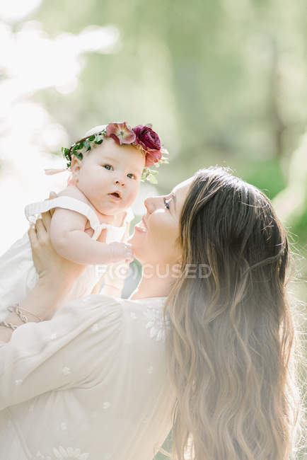Середня доросла жінка позує з дочкою з квітковим вінком на відкритому повітрі . — стокове фото
