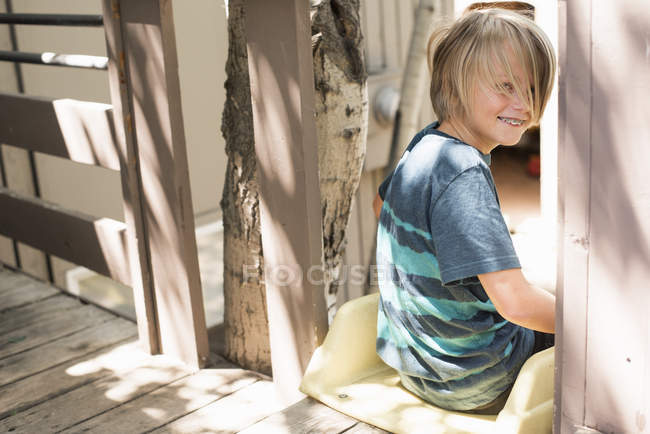 Blonder Junge sitzt auf Klettergerüst im Garten. — Stockfoto