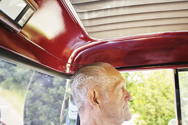 Profile of senior man sitting inside red car. — Stock Photo