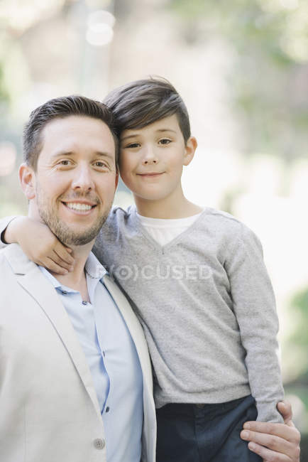 Porträt eines lächelnden Vaters und seines Sohnes, die sich im Freien umarmen. — Stockfoto
