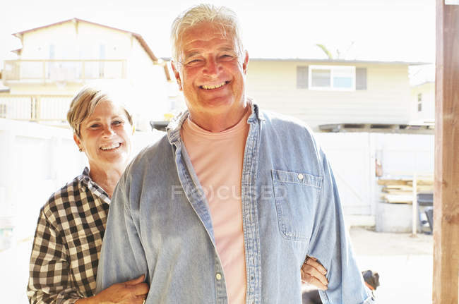 Seniorenpaar lächelt und blickt in die Kamera in Wohnhaus außen. — Stockfoto