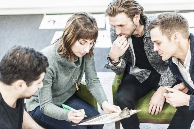 Colleagues at meeting writing with pen on clipboard. — Stock Photo