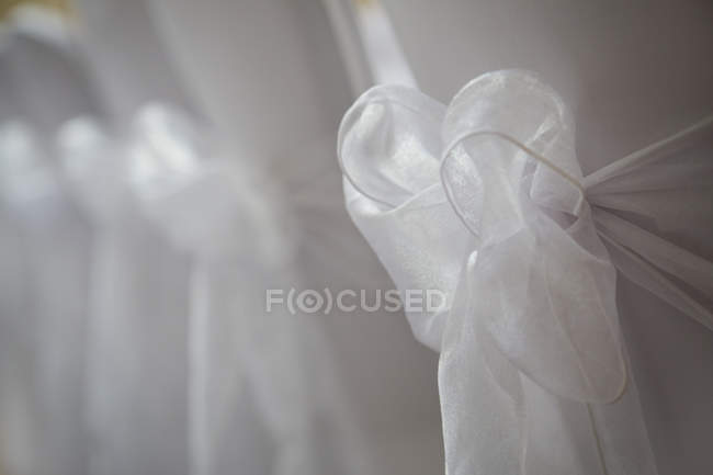 White satin bow tied on chair, close-up. — Stock Photo