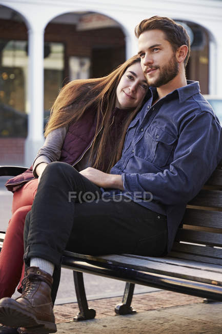 Young couple hugging on bench in urban street. — Stock Photo