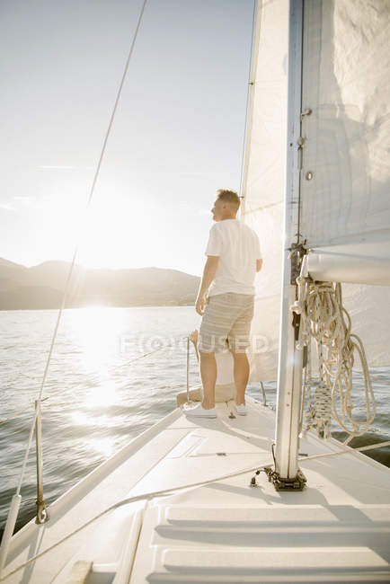 Älterer Mann steht auf Segelboot und blickt auf den See. — Stockfoto