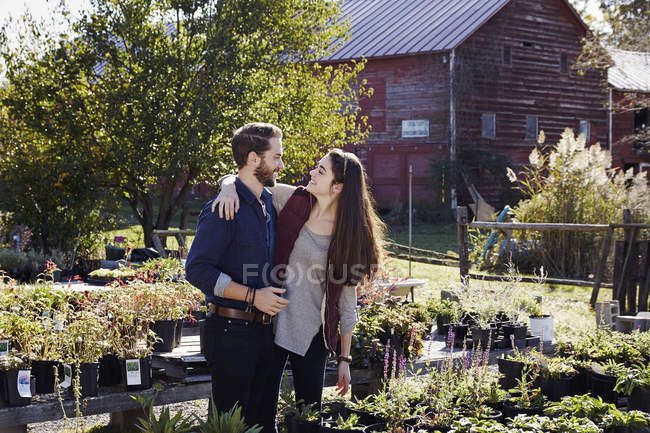 Young man and woman embracing and looking at each other at garden center. — Stock Photo