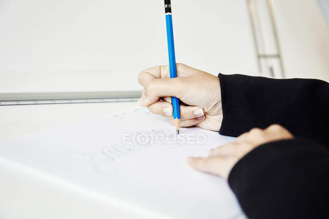 Gros plan des mains féminines travaillant sur le graphique sur la planche à dessin, esquissant des lettres au crayon . — Photo de stock