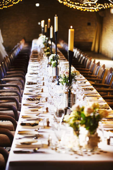 Hochzeitslocation für Party mit Lichterketten und langem Tisch dekoriert. — Stockfoto