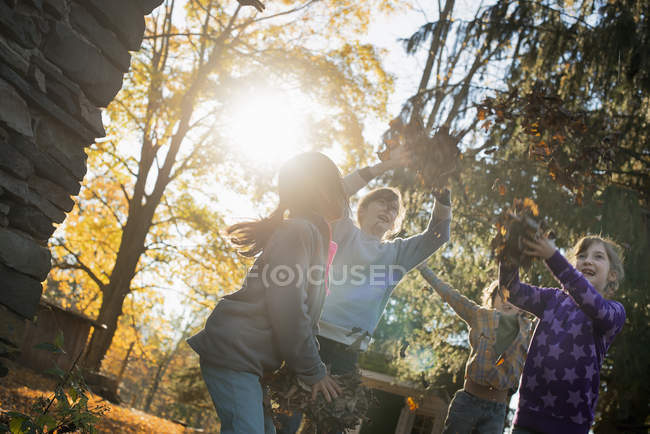 Діти грають на відкритому повітрі і кидали опале листя в Осіннє сонце. — стокове фото