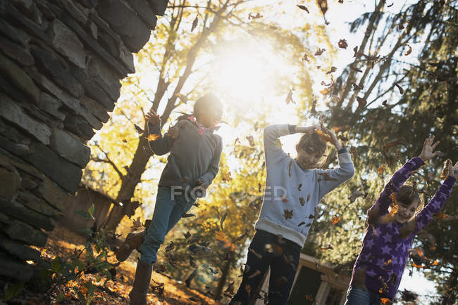 Bambini che giocano all'aperto e gettano foglie cadute in autunno sole . — Foto stock