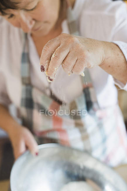 Vista ritagliata della donna che misura e setaccia la farina bianca in ciotola . — Foto stock