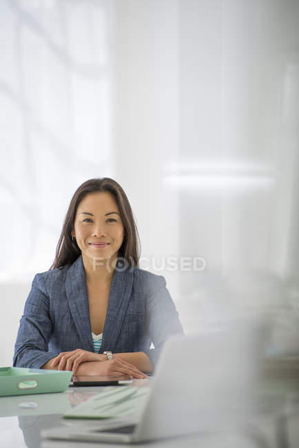 Mujer con los brazos cruzados relajante en el escritorio de la oficina con ordenador portátil y carpeta verde . - foto de stock