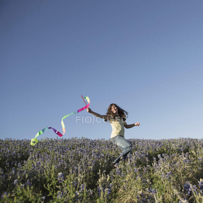 Elementary idade menina correndo com papel streamer fluttering no ar . — Fotografia de Stock