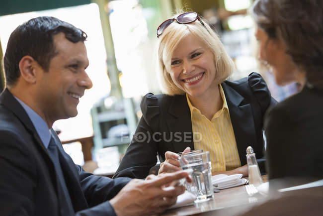 Hombre y mujeres sentados en el bar con bebidas y charlando . - foto de stock